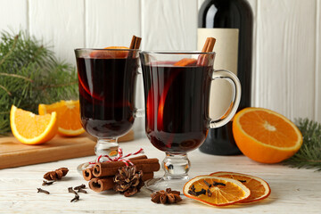 Bottle of wine, cups of mulled wine and ingredients on wooden background