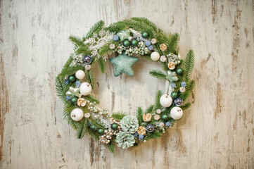 elegant Christmas wreath decorated with green spruce branches, pine cones, berries and toys.