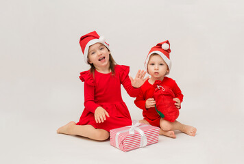 Obraz premium happy little girl and boy in red caps with Christmas gifts on white background with space for text