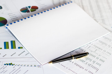 Notepad with text on white background with financial documents and office supplies. Business concept.