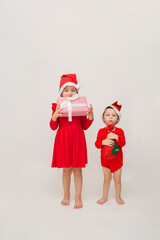 a little girl and a full-length boy in red caps with Christmas gifts on a white background with a copy of the space