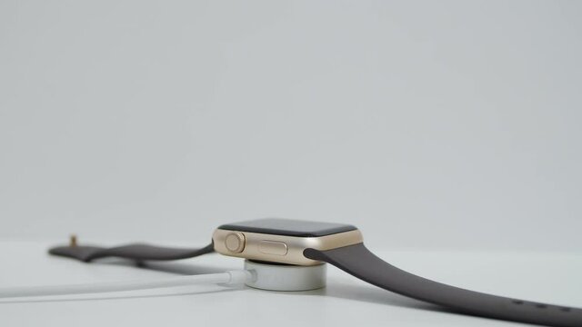 Smart watch charging on wireless charging stand pad on white table