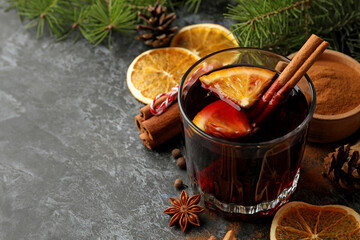 Glass of mulled wine and ingredients on black smokey background