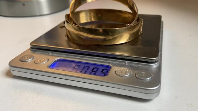 Gold scrap pile chains and bangle  jewelry on weight scale at pawn shop for money 