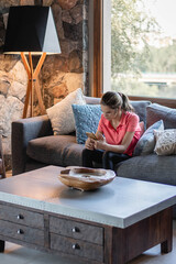 joven alegre con tecnología cerca de ventana en living de su casa 