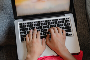 primer plano de manos de joven sobre computadora portátil laptop sobre sillón en su casa no...