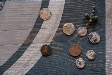 Ancient coins and oxidized copper cross on a wooden surface. Copy space. 
