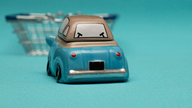 Toy car and shopping cart on blue background. The concept of self-delivery of goods