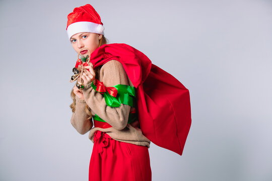 Woman's santa claus carrying a sack with gifts on white background.