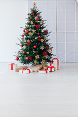 christmas tree with colorful balls and gift boxes over white wall