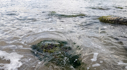 Beach on the sea with waves and stones in water