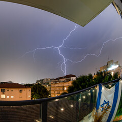 Isolated Israeli Flag with a winter thunderstorm extreme weather in urban setting- Rehovot Israel