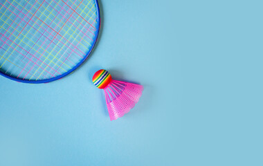 Pink badminton shuttlecock and racket on a blue background. Concept: minimalism, summer outdoor games