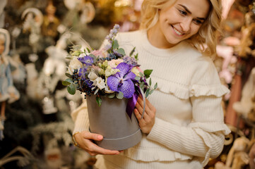 beautiful arrangement of white and purple flowers in round box in hands of blonde woman