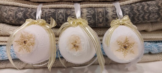 Holiday: Three white Christmas balls with lace, hand-made on a background of multi-colored knitted blankets.