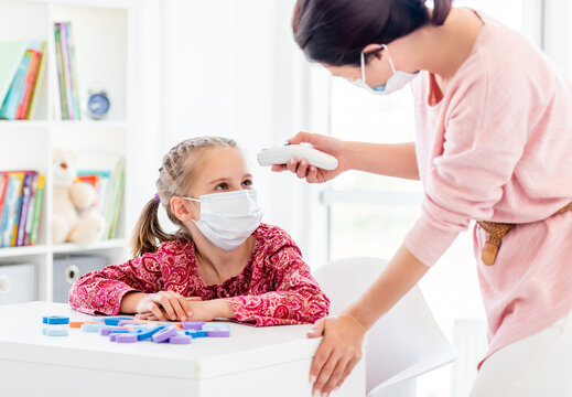 Teacher measuring temperature of pupil with thermometer