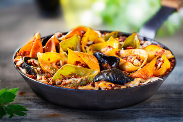 Colorful conchiglioni arlecchino with bolognese sauce
