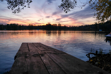 Wooden pier on the lake at sunset reflected in the water