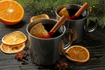 Cups with mulled wine, ingredients and pine branches on wooden background