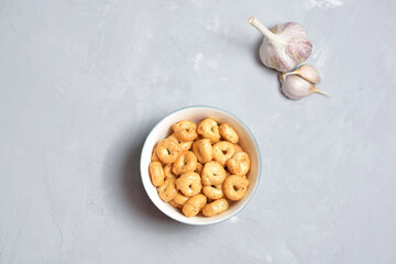 handmade Salty hard round pretzels in gray concrete background. Traditional Italian snack Tarallini with herbs and garlic in ceramic bowl. Small snack rings.