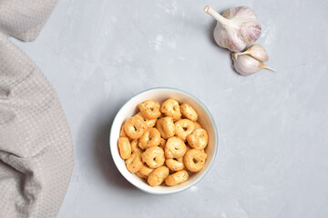 handmade Salty hard round pretzels in gray concrete background. Traditional Italian snack Tarallini with herbs and garlic in ceramic bowl. Small snack rings.