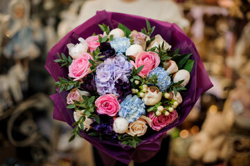 close-up on flowers of gorgeous bouquet wrapped in purple paper