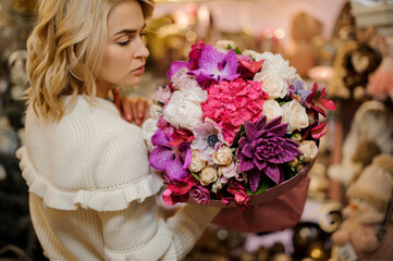 attractive woman holds beautiful bright bouquet of different fresh flowers and succulent decorated with sequins