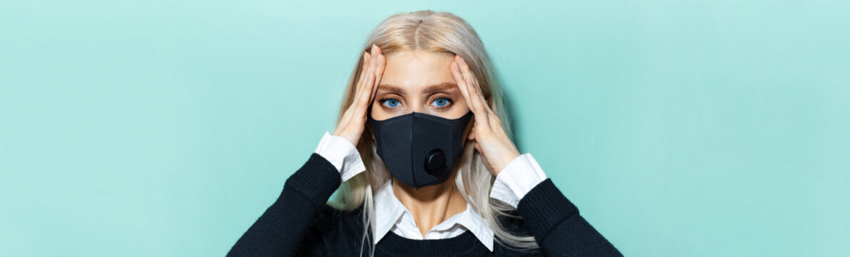 Panoramic Portrait Of Young Blonde Girl Having Headache; Wearing Black Medical Mask On Cyan Background.