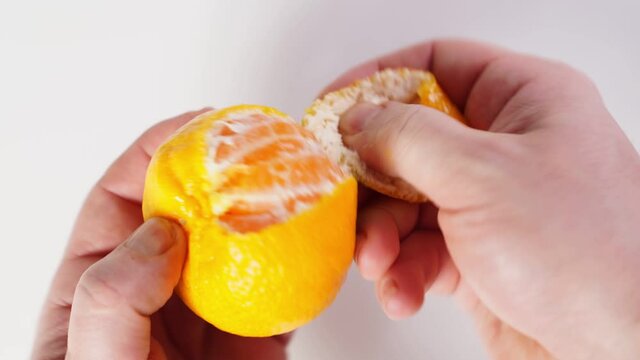 men's hands peel the tangerine and divide it into slices. citrus fruit. symbol of the new year.