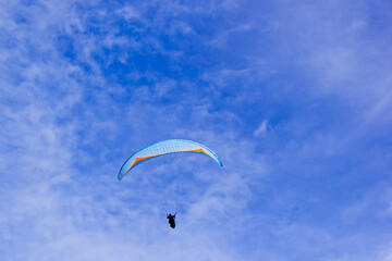 Bright clouds during the day, there are tourists who are skydiving from the hill