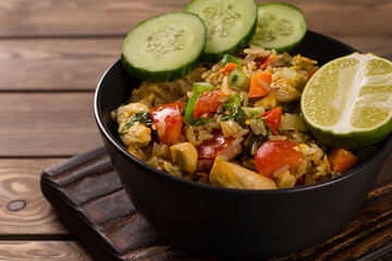 Asian khao pad kung fried rice with vegetables, meat, egg, fresh cucumbers and tomatoes