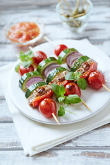 Grilled shashliks with vegetables and pork tenderloin. Bright wooden background. Close up. 