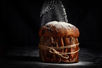 Easter bread. Christmas panettone. Glass sugar falls dusted on the panettone on a dark background.