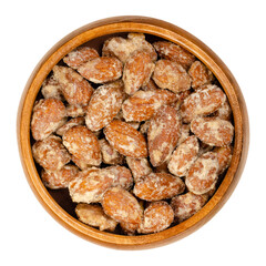 Candied almonds in a wooden bowl. Homemade, in a special way cooked almonds, whole nuts coated in crunchy sugar. Sold at Christmas markets. Close-up, from above, isolated over white, macro food photo.