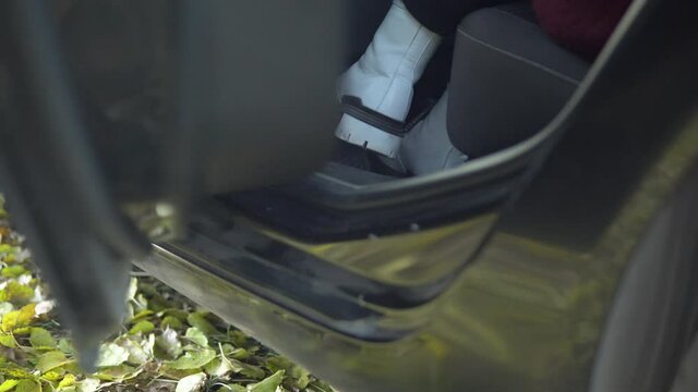 Woman open backdoor and entering car, texi service, autumn fallen leaves on road