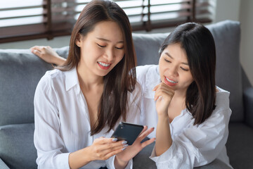 Two asian woman enjoy watching photo on mobile phone at home