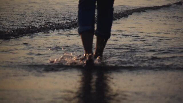 Close up shot of female walking at beach with water splashes. 