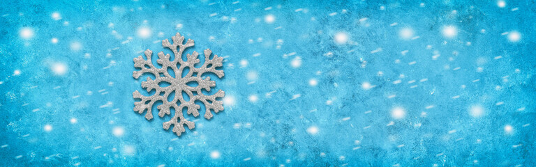 Silver snowflake on a blue grunge background with snow texture, banner. Minimar christmas border. Top view, flat lay.
