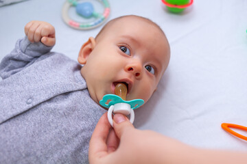 Mother's hands give pacifier to her daughter. Selective focus