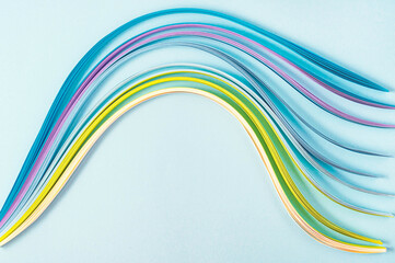 top view of multicolored wavy paper lines on blue background for copy space or logo