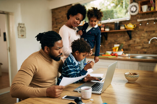African American man trying to work on a computer while being with his family at home.