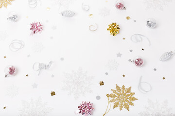 Christmas holiday composition. Festive creative golden pink pattern, xmas decor holiday ball with ribbon, snowflakes on white background.
