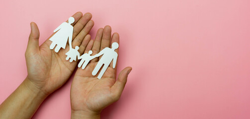 Top view of Hands protect chain family paper on pink background. Family care insurance concept, love and charity, security life, home relationship .