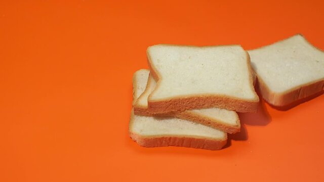 Slices of white bread falling on orange background. Shot of slow motion.