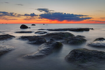 Beautiful colorful sunset over sea and rocks. Baltic sea. Estonia. Long exposure.