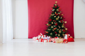 christmas tree with colorful balls and gift boxes over white wall
