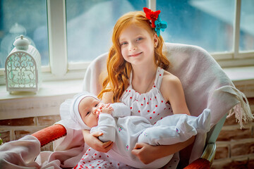 Charming pretty girl teenager holds in her arms her younger newborn sister. Older sister holding body of her little sibling. Concept of Siblings friendly in children. Baby care concept