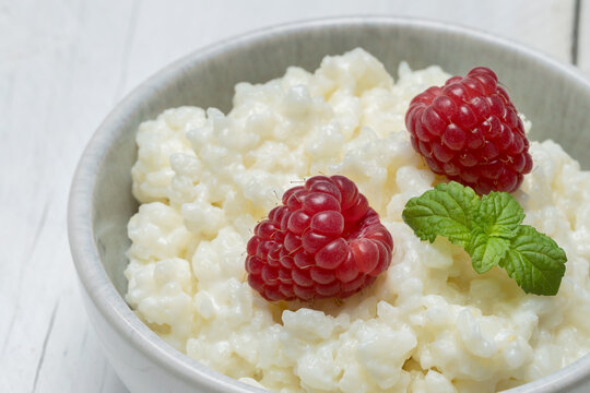 A bowl of rice pudding garnished with raspberries