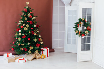 christmas tree with colorful balls and gift boxes over white wall