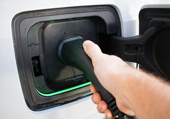 Man plugging in Electric Car At Home Charging Station